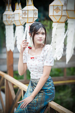 Beautiful Asian woman in traditional Thai dress holding paper lantern during Lanna Loy Krathong festival.