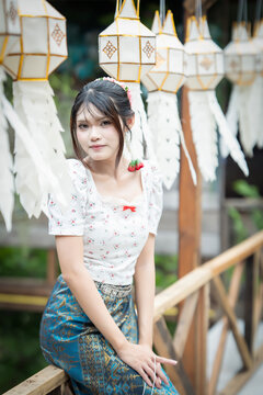 Beautiful Asian woman in traditional Thai dress holding paper lantern during Lanna Loy Krathong festival.