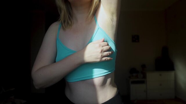 Woman performing breast self examination and checking armpit for lumps. Preventive healthcare routine for early cancer detection and personal wellness.