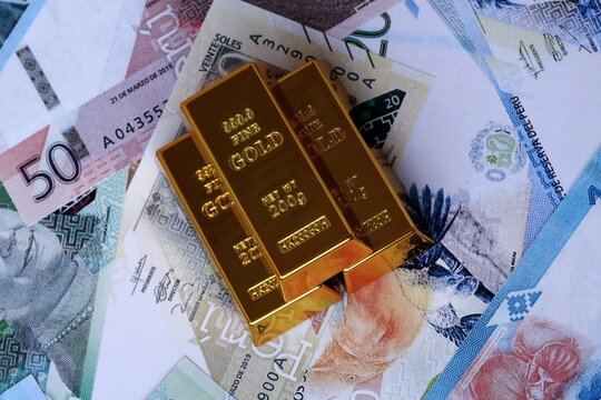 Peruvian sol money bills and gold bullion bars. Peru cash bills of PEN currency close up