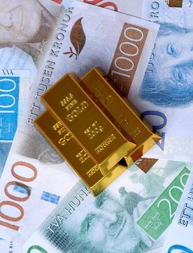 Swedish krona money bills and gold bullion bars. Sweden cash bills of SEK currency close up