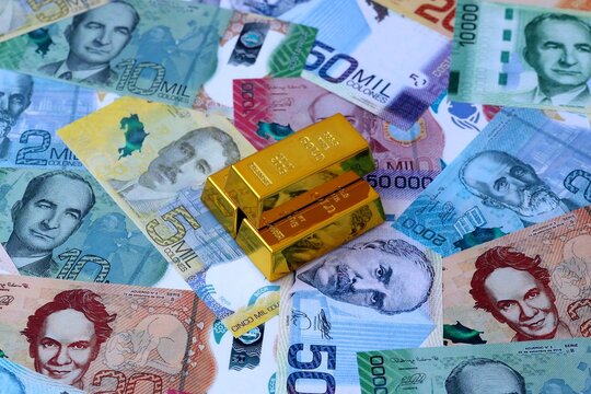 Costa Rican colon money bills and gold bullion bars. Costa Rica cash bills of CRC currency close up