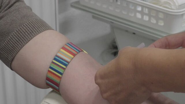 Close-up of a venous blood collection procedure. A healthcare worker takes a blood sample from a patient's arm using medical equipment