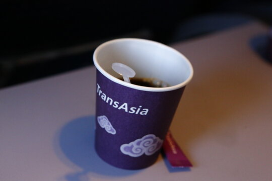 Inflight hot drink paper cup on airplane tray table.