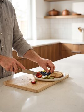 Adult person preparing a simple healthy breakfast in a modern home kitchen with fresh fruit, toast and everyday kitchenware.