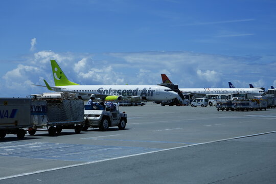 Solaseed Air passenger airplane parked on tarmac with airport ground support vehicles under blue sky.