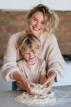 Smiling mother holding son while mixing dough in kitchen for family lifestyle portrait and vertical background showing joyful domestic bonding