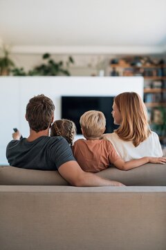 Cozy family on couch watching television together at home for lifestyle background and banner design