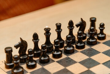 playing chess, black chess pieces are placed in rows on black and white chessboard before game beginning © Anton Pentegov