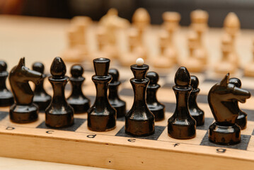 playing chess, black and white chess pieces are placed in rows on chessboard before game beginning © Anton Pentegov