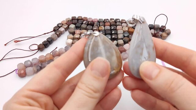Assortment of polished natural gemstone pendants featuring unique mineral patterns arranged next to colorful faceted cube bead strands on a clean surface