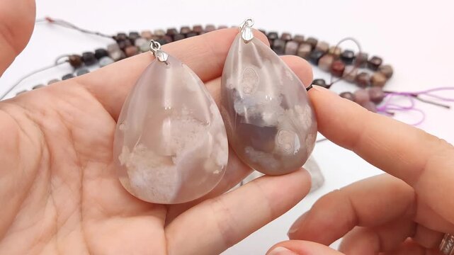 Assortment of polished natural gemstone pendants featuring unique mineral patterns arranged next to colorful faceted cube bead strands on a clean surface