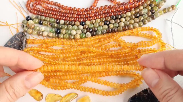 Diverse collection of colorful gemstone bead strands and polished natural stone pendants displayed neatly on a bright white surface for creative jewelry design projects