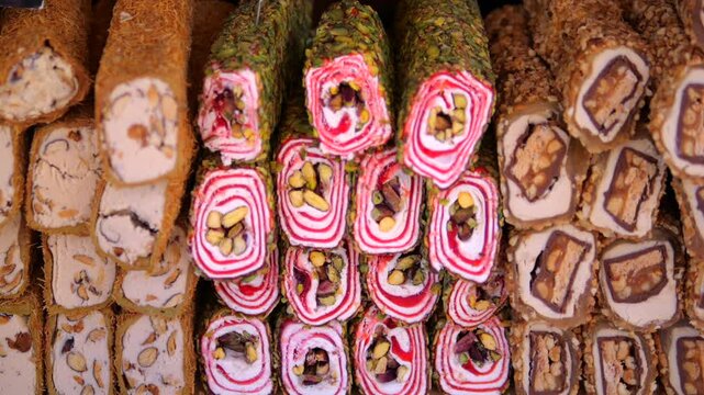 Rows of sliced sweets create abundant dessert display, revealing colorful swirls, chocolate layers, and nut filled centers. Overhead view emphasizes variety and craftsmanship of confectionery.