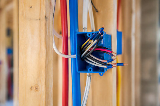 Electrical wiring connections are being made inside a wooden structure.