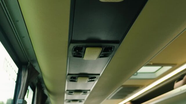 Bus ceiling ventilation system with individual air vents and reading lights. Overhead passenger service panels along modern intercity coach cabin. Long distance transport interior equipment above