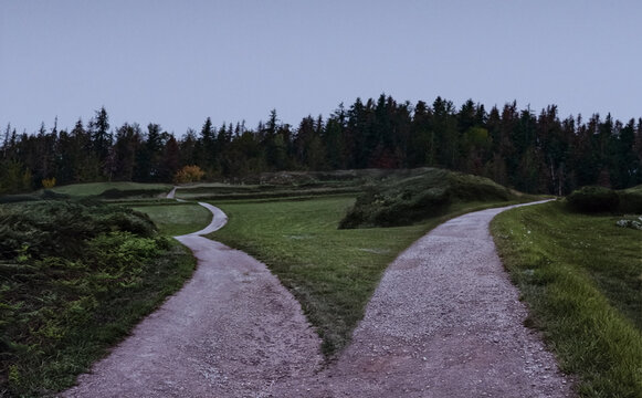 Two dirt paths diverging at dusk representing life choice and decision concept.