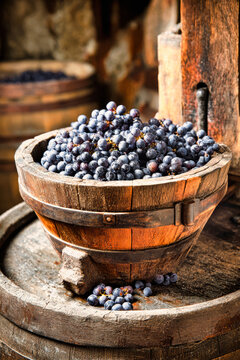 Grapes are pressed in a wooden winery, with a funnel-hopper atop