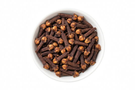 Whole dried cloves in a small white ceramic bowl viewed from above