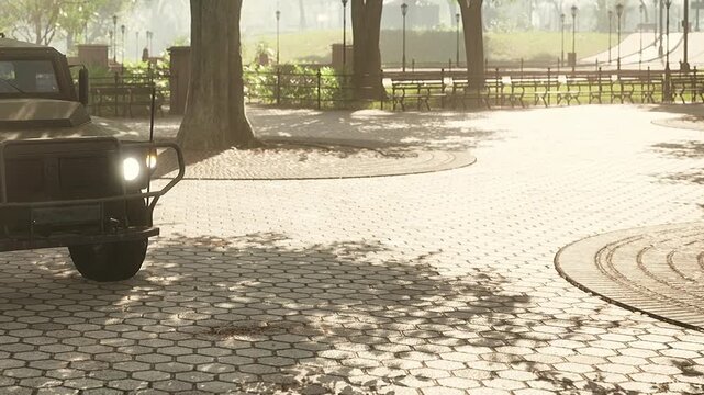A vintage vehicle rests on a sunlit cobblestone path in a peaceful park. Trees cast long shadows while benches and pathways invite visitors to enjoy the beautiful day.