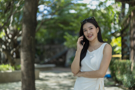 Asian woman smiling while talking on mobile phone in a park
