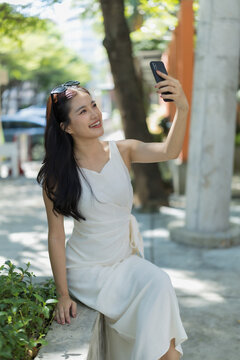 Woman making selfie with smartphone in city park, enjoying sunny day outdoors