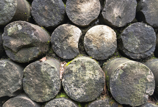 Close-up of Weathered cylindrical stone pillars stacked in harmonious symmetry, displaying the organic rugged textures and subtle moss patina of ancient craftsmanship at Dazu. The rough, weathered cro