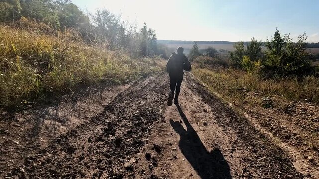 Volunteers in protective uniform jogging on dirty country road at frontline city in Ukraine. Rescue workers running to help animals and people from areas shelled by russian army. Slow mo