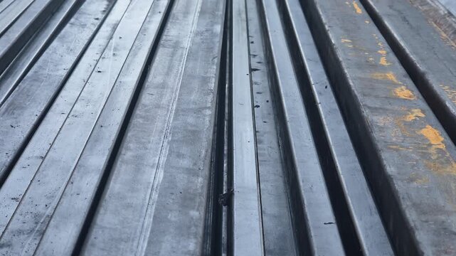 Steel metal profile square tubes stacked on the ground at an outdoor industrial site