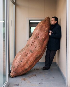 Giant Sweet Potato in a Tiny Elevator. Man squeezed against wall