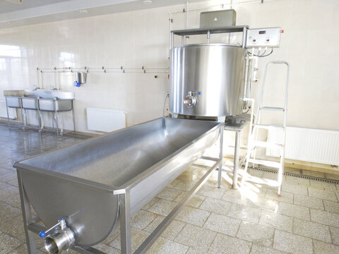 A cylindrical metal tank connected to a long rectangular bath. Dairy shop. Ripening and salting of cheeses and feta cheese. Cheese production.