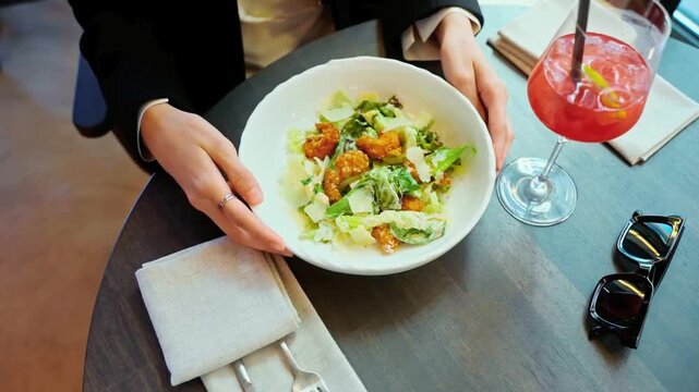 Business woman having a healthy caesar salad lunch with a refreshing cocktail at a restaurant table