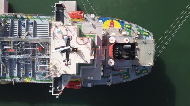 4K drone footage flying sideways above an oil tanker from stern to bow. Ships moors at port unloading fuel. Detailed deck pipelines, manifolds, lifeboats, superstructure. Original footage.