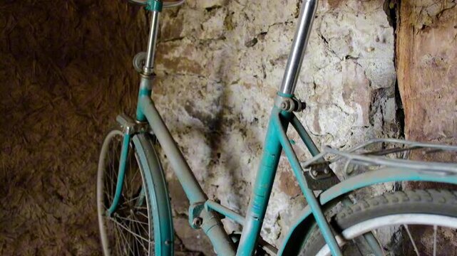 Close up of retro green bicycle standing in rustic stone workshop
