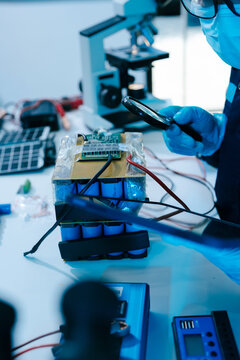 Engineer testing a battery pack with a multimeter in a high-tech lab, exploring BMS, renewable energy storage, electrical testing, clean power, and battery innovation.