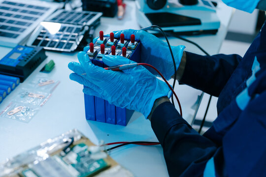 Engineer testing a battery pack with a multimeter in a high-tech lab, exploring BMS, renewable energy storage, electrical testing, clean power, and battery innovation.