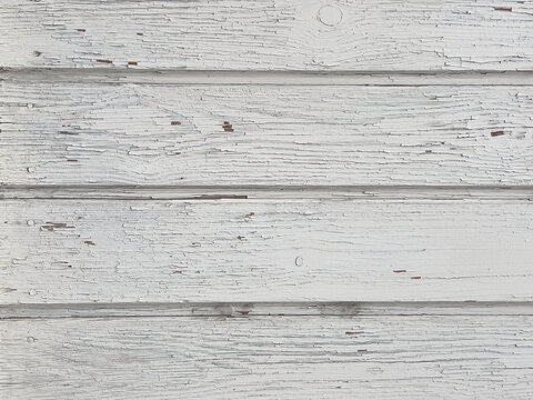 Weathered horizontal wooden siding with cracked peeling white paint, background 