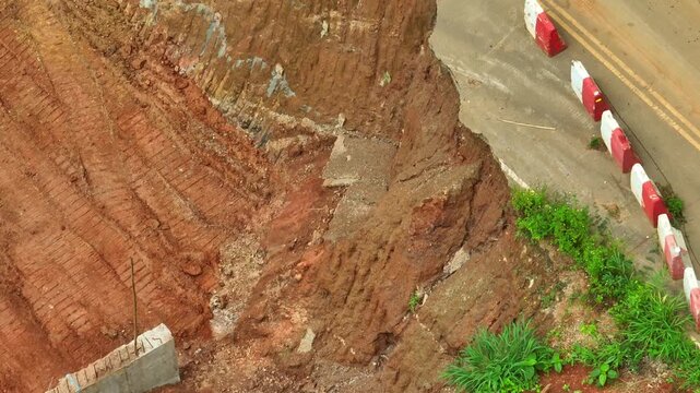 Aerial view captures a collapsed mountain road embankment surrounded by exposed soil, highlighting landslide risks, structural damage, slope reinforcement, and essential road maintenance. Thailand.
