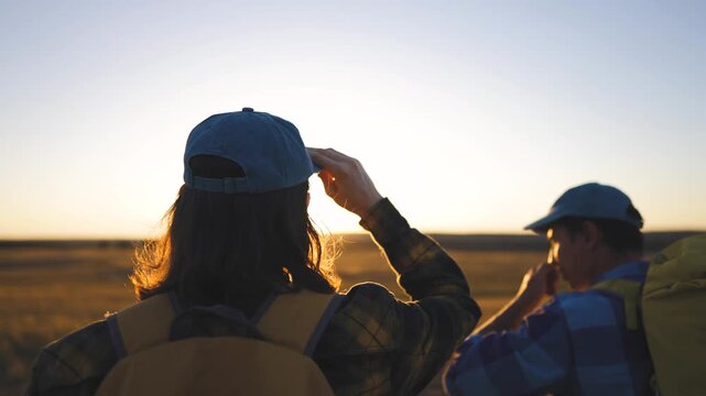 Team hiking walk freedom. The man and boy walk towards the sunset, enjoying the scenic view. The man and boy share a moment, wearing hats and backpacks while appreciating nature.