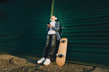 Teenager listening to music with headphones and skateboard © djile