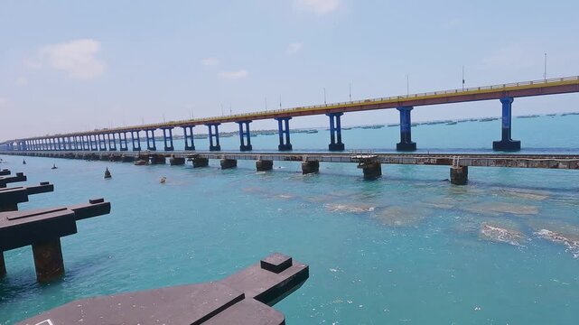 POV video from a moving train crossing Pamban Railway Bridge near Rameswaram, Tamil Nadu, India, showcasing the railway tracks, turquoise seawater, and parallel bridge structure along the coast.
