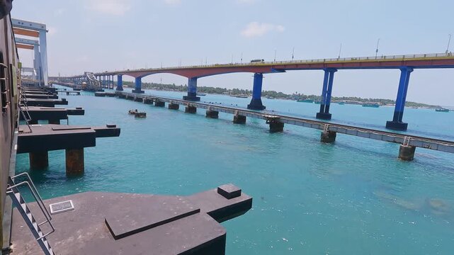 POV video from a moving train crossing Pamban Railway Bridge near Rameswaram, Tamil Nadu, India, showcasing the railway tracks, turquoise seawater, and parallel bridge structure along the coast.