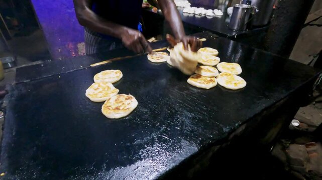 Video of a street food vendor cooking fresh parathas on a large hot griddle at a roadside restaurant in South India, showcasing Indian cuisine and everyday food preparation.
