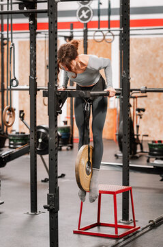 Fitness woman performing weighted parallel bar dips in gym