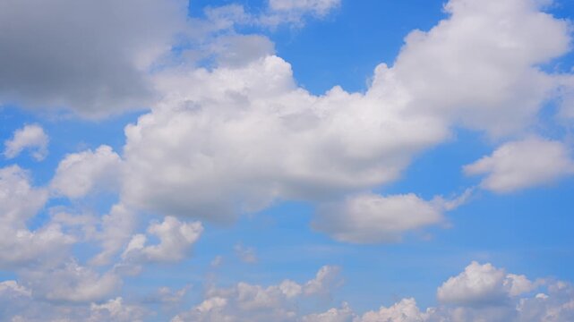 Sunlight filters through massive cotton-like cumulus clouds in a captivating timelapse, highlighting their billowing textures, shifting shadows, and evolving formations against a brilliant azure sky.
