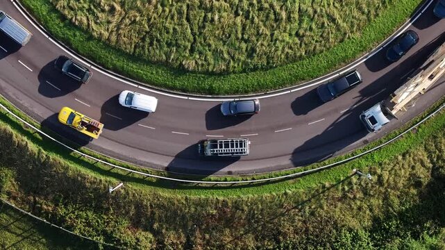 A highangle drone perspective shows vehicles navigating a circular road junction, featuring a large truck transporting a modular flat packed home. Ideal for logistics and construction themes.