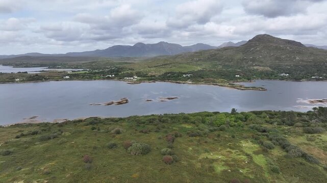 A sweeping aerial shot showcasing the rugged Twelve Bens mountain range and serene lake waters in Connemara, Ireland. Captures the authentic beauty of the Irish wilderness.