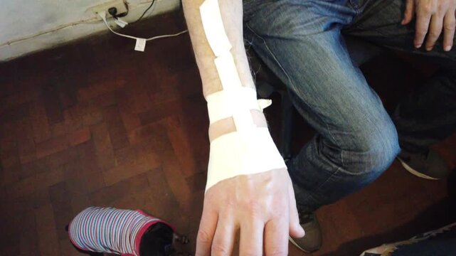 Closeup of Elderly Man Hand and Bandaged Wrist After Catheter Procedure During Medical Recovery