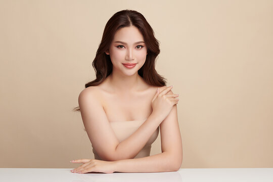 A beautiful young Asian woman with clean, fresh skin against a beige background. Skincare, facial treatment, cosmetology, beauty, and spa. An elegant portrait of an Asian woman.