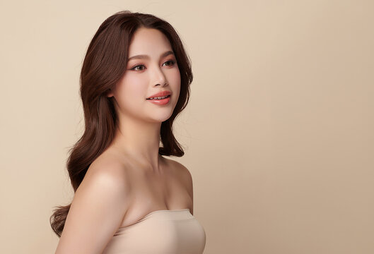 A beautiful young Asian woman with clean, fresh skin against a beige background. Skincare, facial treatment, cosmetology, beauty, and spa. An elegant portrait of an Asian woman.